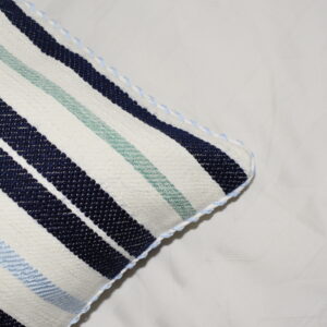 Détail de la housse de coussin tissée et cousue à la main avec des rayures bleu marine, bleu ciel et vert d'eau